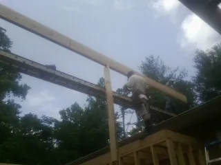 Carpenter setting a ridge beam over a new addition frame — Ice Dam Removal by Roofing Brothers in Puryear