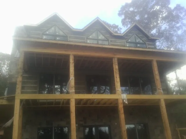 Dormers and porch framing on a large log home under construction — Roof Coating work by our crew in Puryear