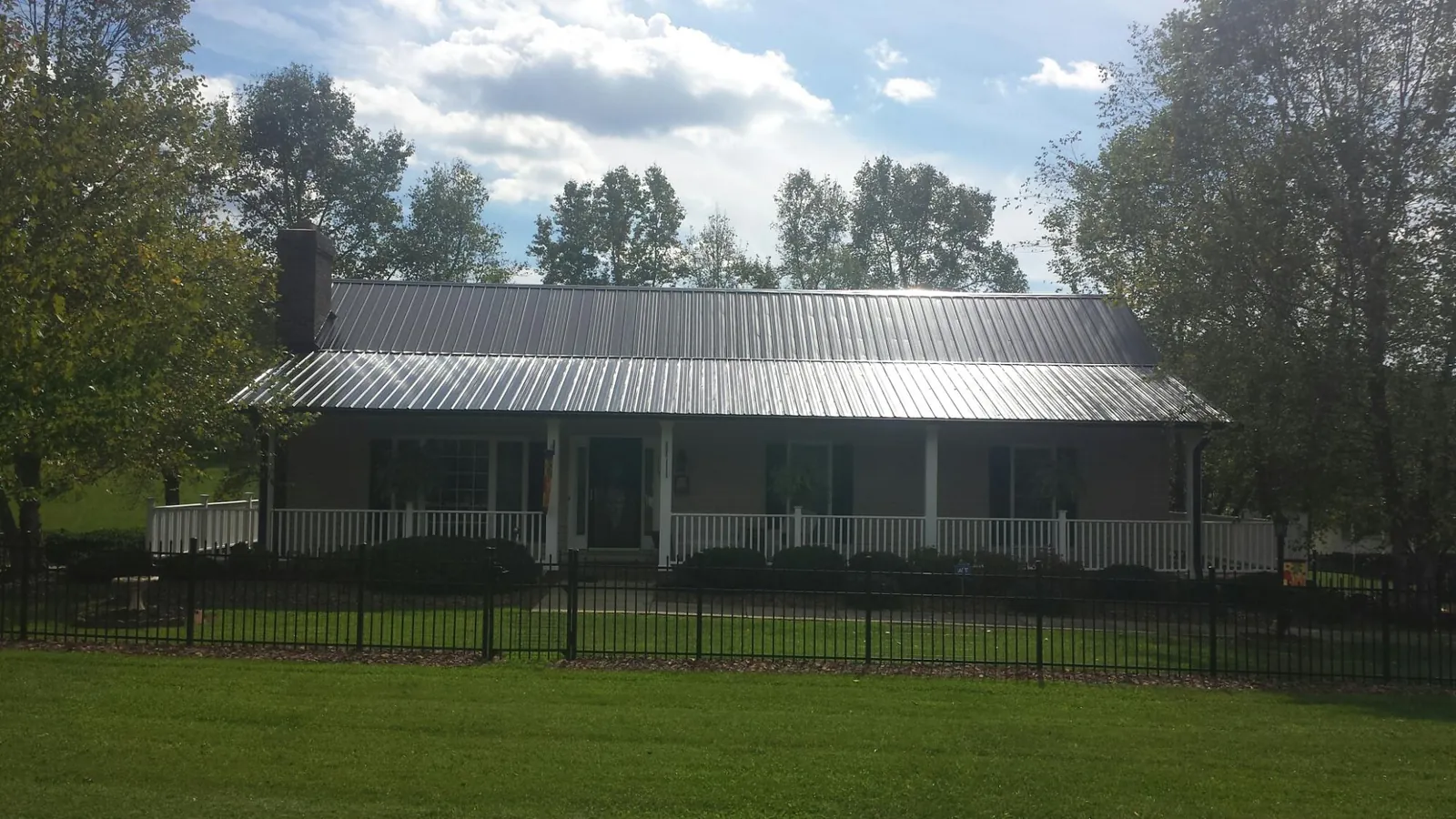 Gray metal roof on a brick ranch with a full width front porch — Gutter Guard Installation work by our crew in Puryear
