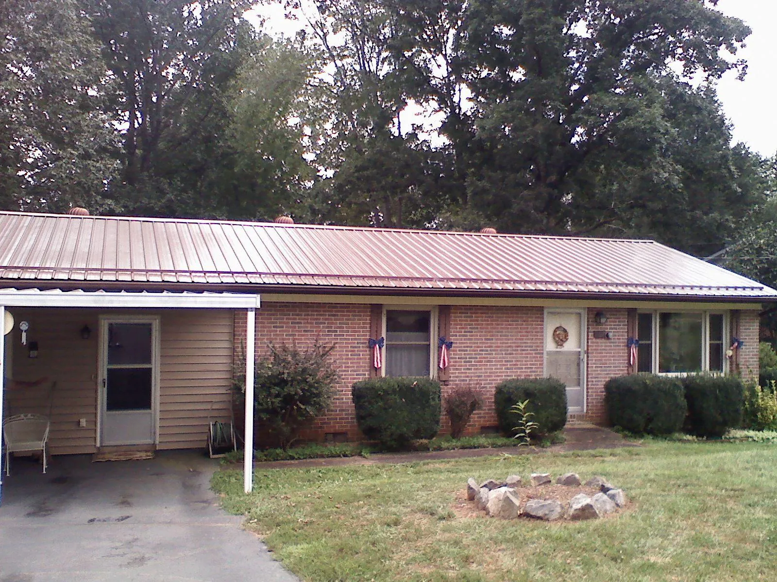 Bronze metal roof and carport on a brick ranch home — Roof Repair work by our crew in Puryear