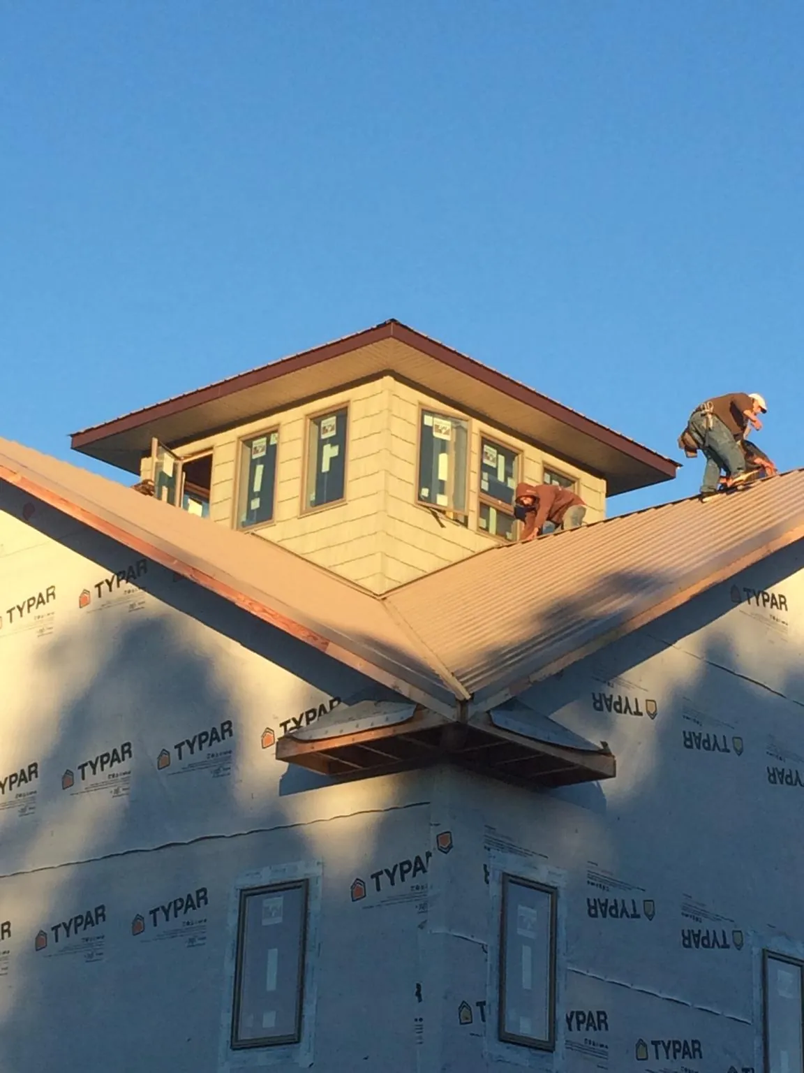 Roofers working around a rooftop cupola on a new metal roof at sunset — Roof Waterproofing in Puryear by Roofing Brothers